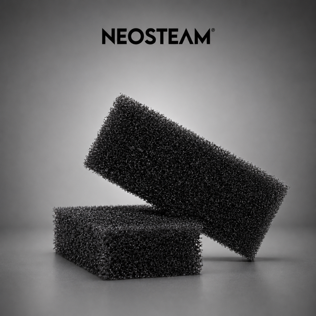 65 - NeoSteam Two black porous foam blocks stacked diagonally on a gray surface, with the NEOSTEAM logo above.